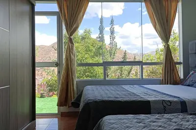 a bedroom with two beds and a large window at Qori Garden Apartment in Cusco