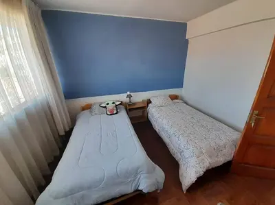 two beds in a bedroom with a blue wall at Departamento en el centro histórico del Cusco in Cusco