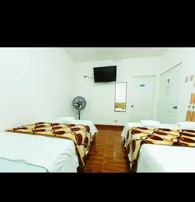 a room with two beds and a flat screen tv at ALOJAMIENTO ISLA BLANCA in Paracas
