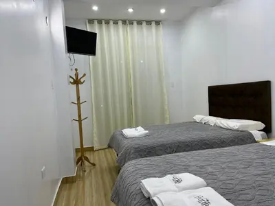 a hotel room with two beds and a flat screen tv at Hurin Hotel in Ica