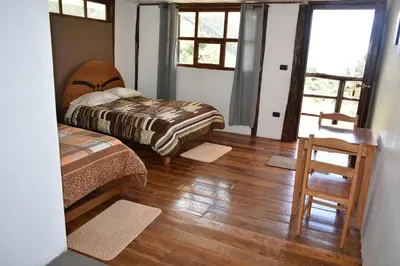 a bedroom with two beds and a wooden floor at CasaNostra Choquequirao in Cachora