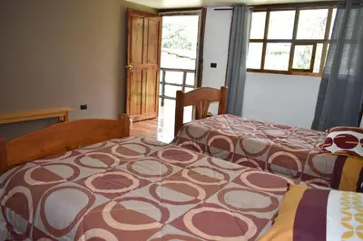 a bedroom with two beds and a window and a door at CasaNostra Choquequirao in Cachora