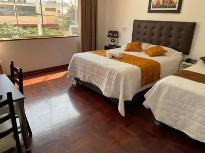 a hotel room with two beds and a window at Lima HOUSE MILANI in Lima