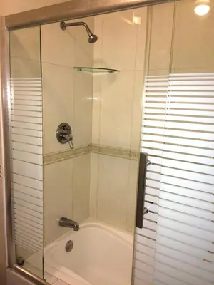 a shower with a glass door next to a tub at Hotel Princesa in Lima