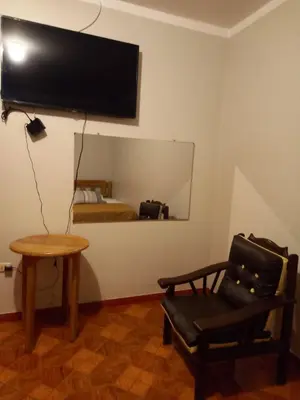 a room with a chair and a television and a bed at Hospedaje TOSCANO SUITES in Huancayo