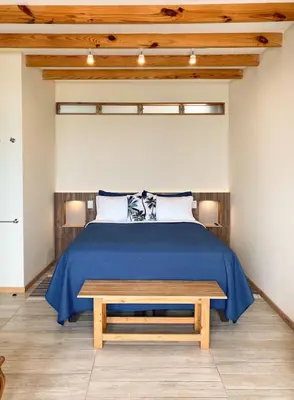 a bedroom with a bed and a wooden bench at Kauhuhu Casa Hotel in San Bartolo