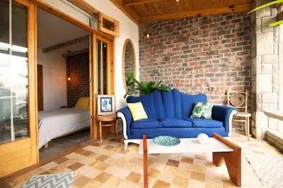 a living room with a blue couch and a brick wall at Kauhuhu Casa Hotel in San Bartolo