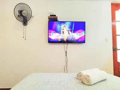 a flat screen tv hanging on a wall in a bedroom at Hermosa Habitación c/ Baño privado - Huacachina. in Ica