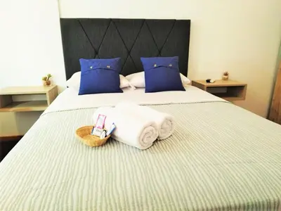 a bedroom with a bed with towels and blue pillows at Hermosa Habitación c/ Baño privado - Huacachina. in Ica