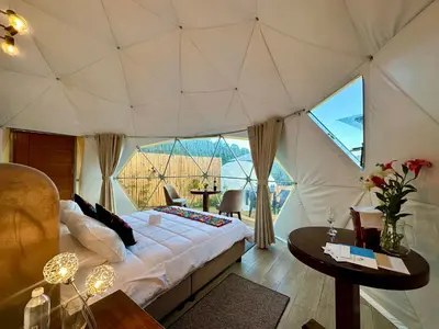 a bedroom with a tent with a bed and a table at MISKI SAMAY DOMO BOUTIQUE in Urubamba