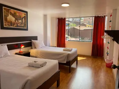 a hotel room with two beds and a window at Adriano's Deluxe Apartments 3 in Cusco