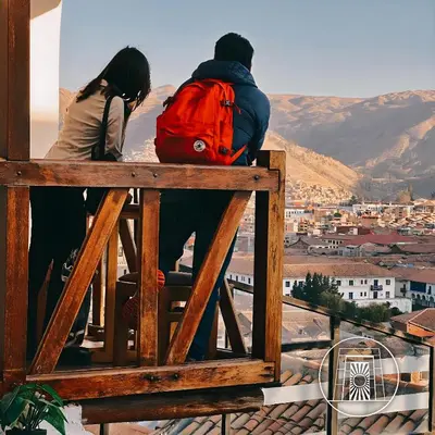 a man and a woman sitting on a fence looking at a city at Casa Cusco guest house in Cusco