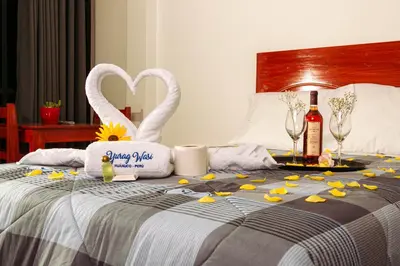 a bed with two swans and flowers and wine bottles at YURAQ WASI Hotel/Restobar in Huánuco