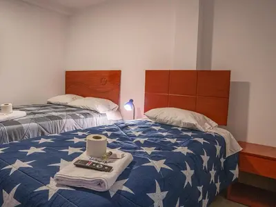a bedroom with two beds with a blue and white comforter at YURAQ WASI Hotel/Restobar in Huánuco