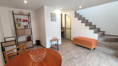 a living room with a table and a staircase at QORI, apartamento nuevo Centro Histórico de Cusco, Cuesta San Blas 561 in Cusco