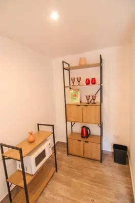 a room with a microwave and a table and shelf at QORI, apartamento nuevo Centro Histórico de Cusco, Cuesta San Blas 561 in Cusco