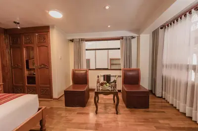 a bedroom with a bed and two chairs and a table at Quechua Hotel Cusco in Cusco