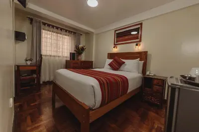 a bedroom with a large bed with wooden floors at Quechua Hotel Cusco in Cusco