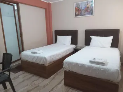 a hotel room with two beds and a chair at CARDOS HOSTAL in Pisco