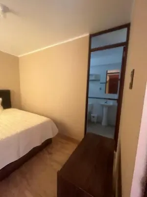a bedroom with a bed and a bathroom with a mirror at CARDOS HOSTAL in Pisco