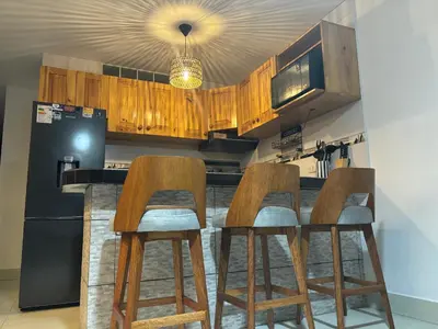 a kitchen with wooden cabinets and a black refrigerator at Comfortable House in Punta Hermosa