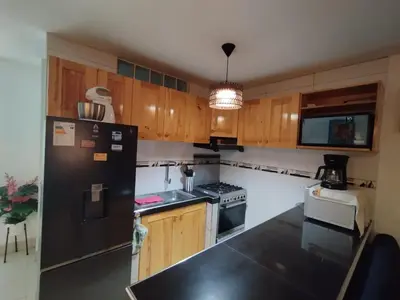 a kitchen with wooden cabinets and a black refrigerator at Comfortable House in Punta Hermosa
