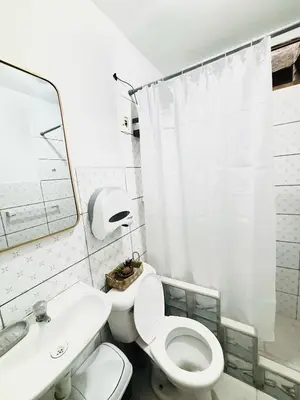 a white bathroom with a toilet and a sink at Comfortable House in Punta Hermosa