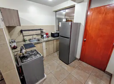 a small kitchen with a refrigerator and a stove at Zisary's House Apartment in Cusco