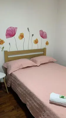 a bedroom with a bed with flowers on the wall at Lindo depa san miguel, 3camas, wifi, terraza. in Lima