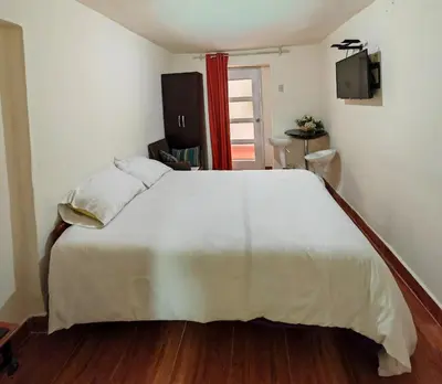 a bedroom with a large white bed and wooden floors at Centro Cusco Inti Saphy in Cusco