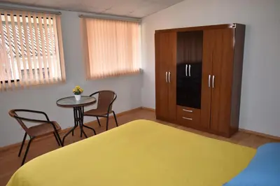 a bedroom with a bed and a cabinet and a table at saga andina in Cusco