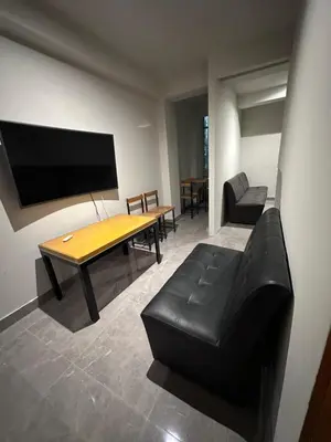 a living room with a black leather couch and a table at Dpto a 3 min Plaza Huánuco y 1 cuadra Open Plaza in Huánuco