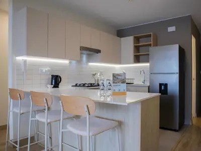 a kitchen with a counter with stools and a refrigerator at Pod by Wynwood House in Lima