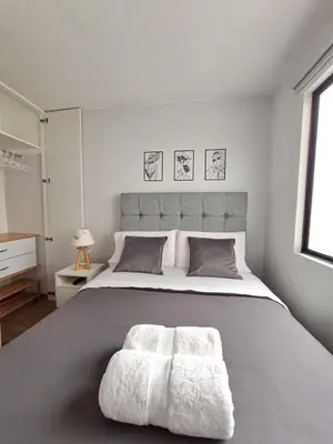 a white bedroom with a large bed with a large headboard at Miraflores - Dormitorio en Departamento compartido Baño Exclusivo Externo in Lima