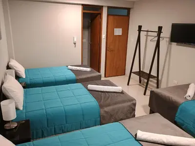 a hotel room with three beds and a television at Vianca Hotel in Machu Picchu