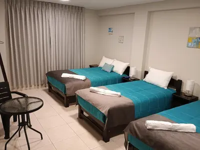 a hotel room with three beds with blue sheets at Vianca Hotel in Machu Picchu
