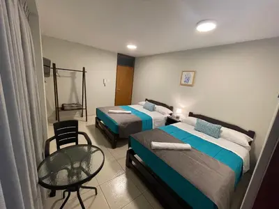 a hotel room with two beds and a table and chair at Vianca Hotel in Machu Picchu