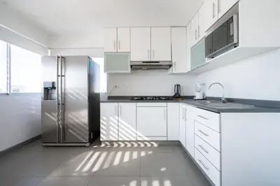 a kitchen with white cabinets and a stainless steel refrigerator at Sotavento Oceanfront Condos by Vibrant in Paracas