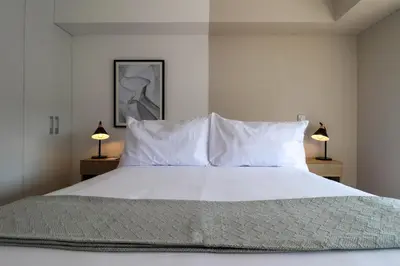 a bedroom with a bed with white sheets and two lamps at Gray by Wynwood House in Lima