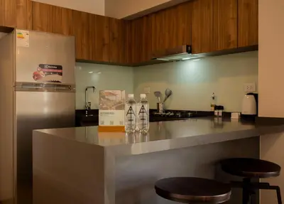 a kitchen with a counter with stools and a refrigerator at Gray by Wynwood House in Lima