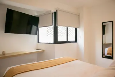 a bedroom with a bed and a tv and a window at Gray by Wynwood House in Lima
