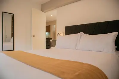 a bedroom with a bed with white pillows and a mirror at Gray by Wynwood House in Lima