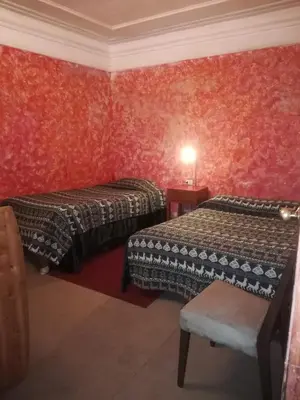 a room with two beds and a chair in it at Royal Frankenstein Hostel in Cusco
