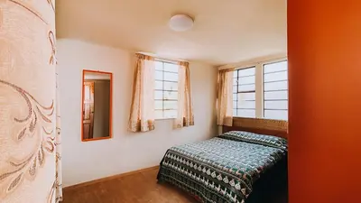 a bedroom with a bed and two windows at Royal Frankenstein Hostel in Cusco
