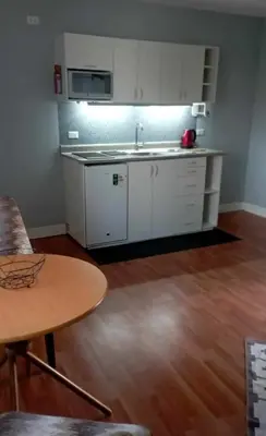 a kitchen with white cabinets and a sink and a table at Live, Work & Comfort San Isidro in Lima