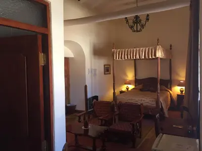 a bedroom with a canopy bed and two chairs at Hotel Midori in Cusco