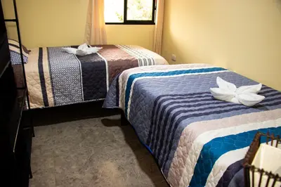 a room with two beds with white flowers on them at La casa de Anni - Departamento 1 in Oxapampa