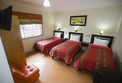 a hotel room with two beds and a chair at Hotel Tinkus Inn in Lima