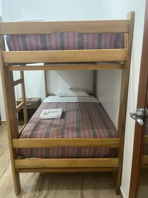 a wooden bunk bed in a small room at Mini Hostal Cardos in Pisco
