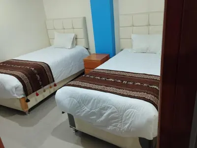two twin beds in a room with a blue wall at hotel plaza chinchero in Cusco